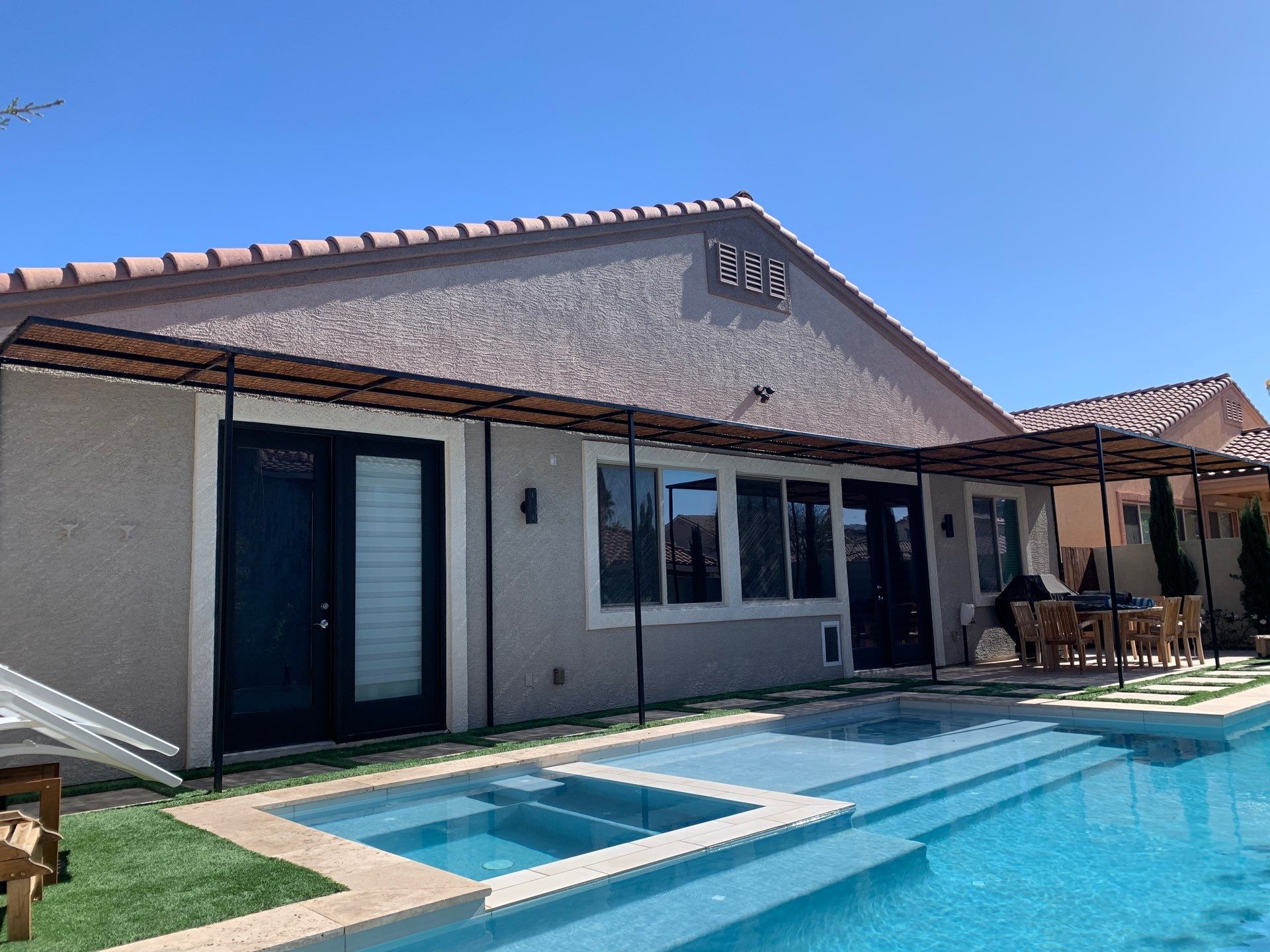 House with a rectangular pool, outdoor seating area, and covered patio; light stucco exterior.