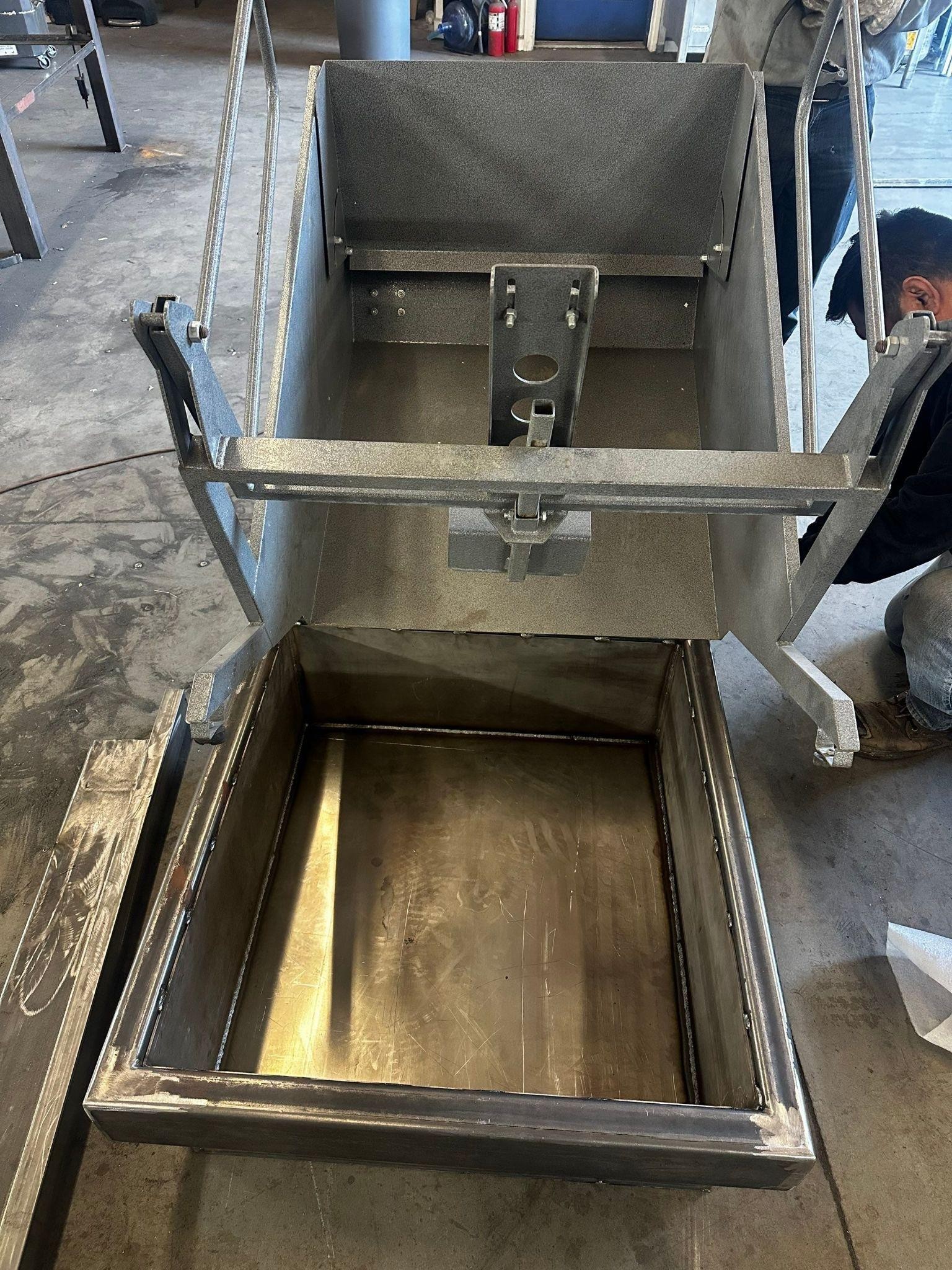 Open stainless steel rectangular hopper with an inner bottom tray, mounted on a metal frame.