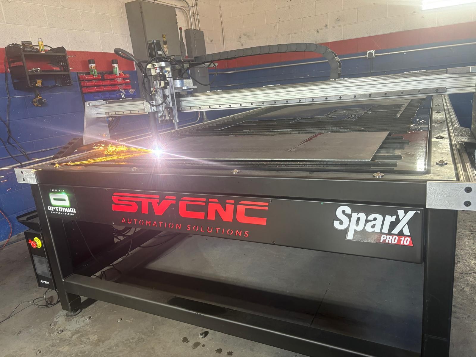 Industrial laser cutting machine labeled SVNC SparX Pro with a metal sheet in the bed.