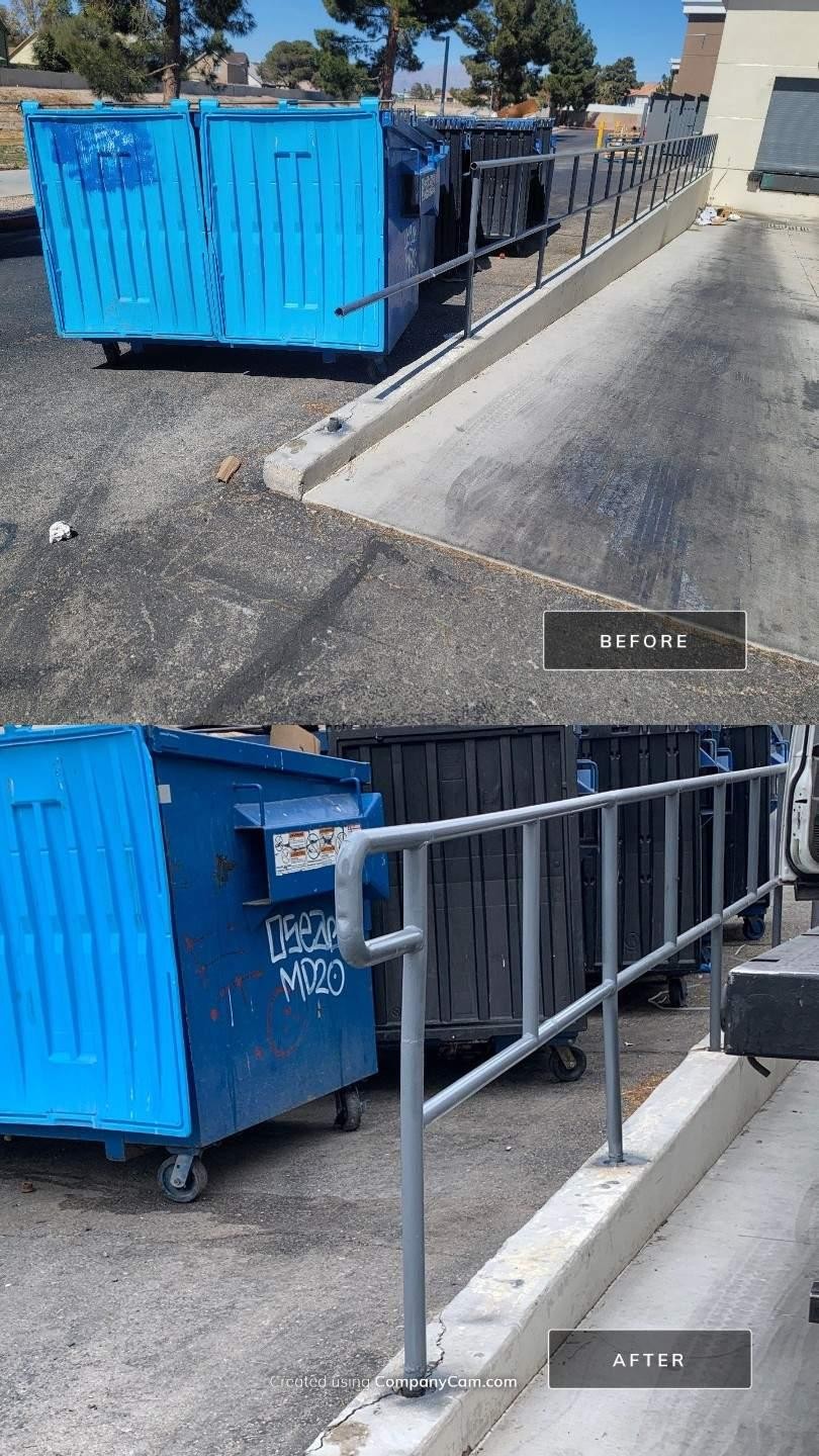 Blue industrial dumpster on a rooftop next to a metal railing and concrete surface.